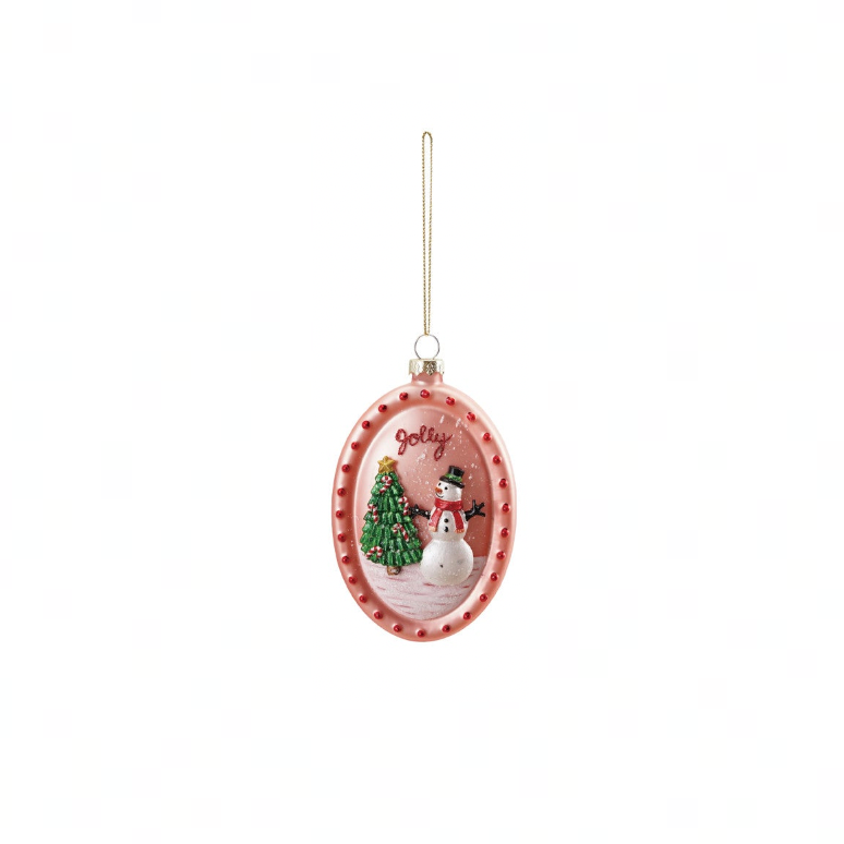 An oval Christmas ornament with a pink bottle-cap style border and a hanging loop, featuring a festive scene of a snowman, Christmas tree, and the word 'Joy' on a white background.