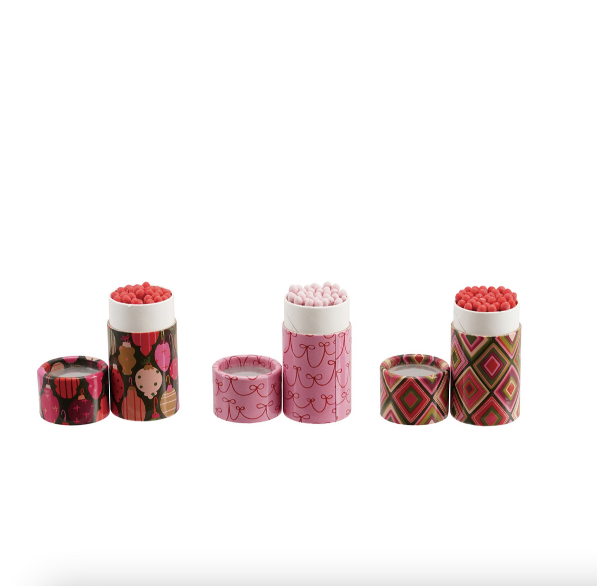 Three small cylindrical patterned match boxes with lids, shown open and closed on a plain white background. The boxes have pink, red, green, and brown geometric and floral patterns, and the tops are filled with small round pink candies or beads.