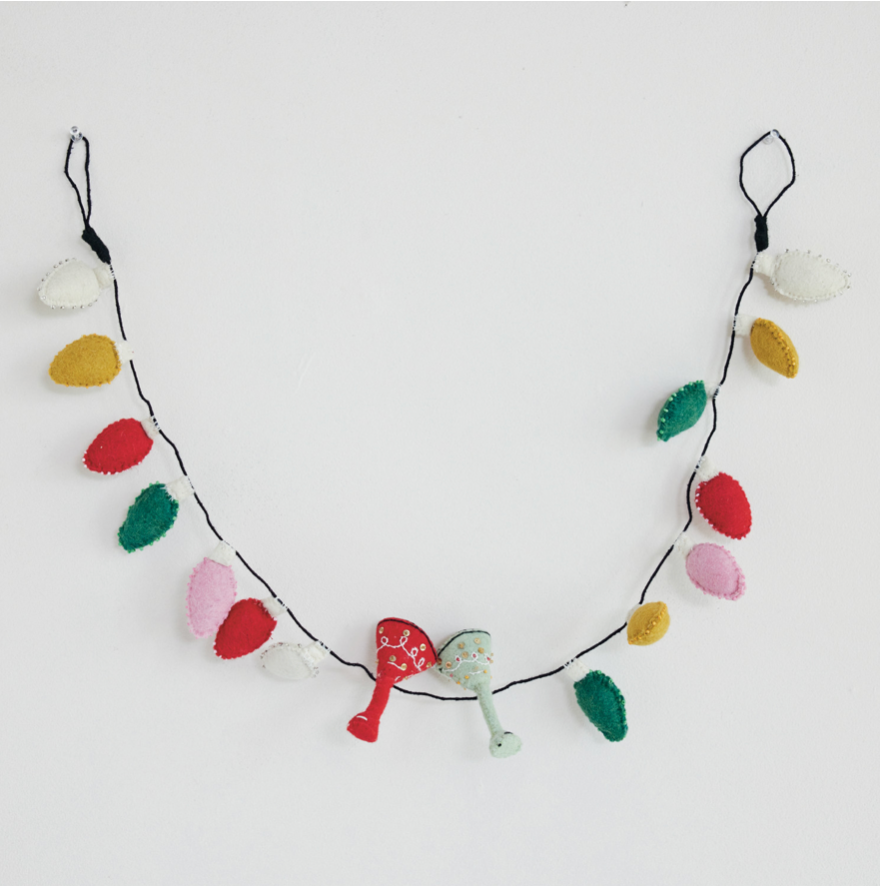 A felt Christmas garland with colorful felt light bulbs and two small felt cocktail glass ornaments hanging from a black string on a plain white background.