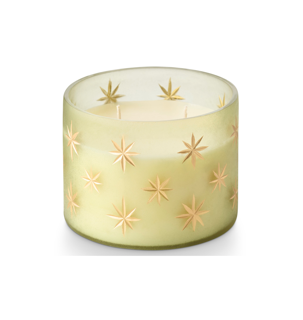 A frosted glass candle holder with a pale yellow-green tint and embossed star patterns, containing white wax, set against a plain white background.
