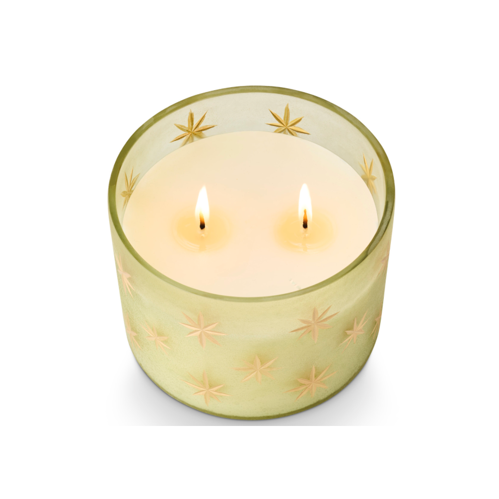 A frosted glass candle holder with a pale yellow-green tint and embossed star patterns, containing white wax, set against a plain white background.