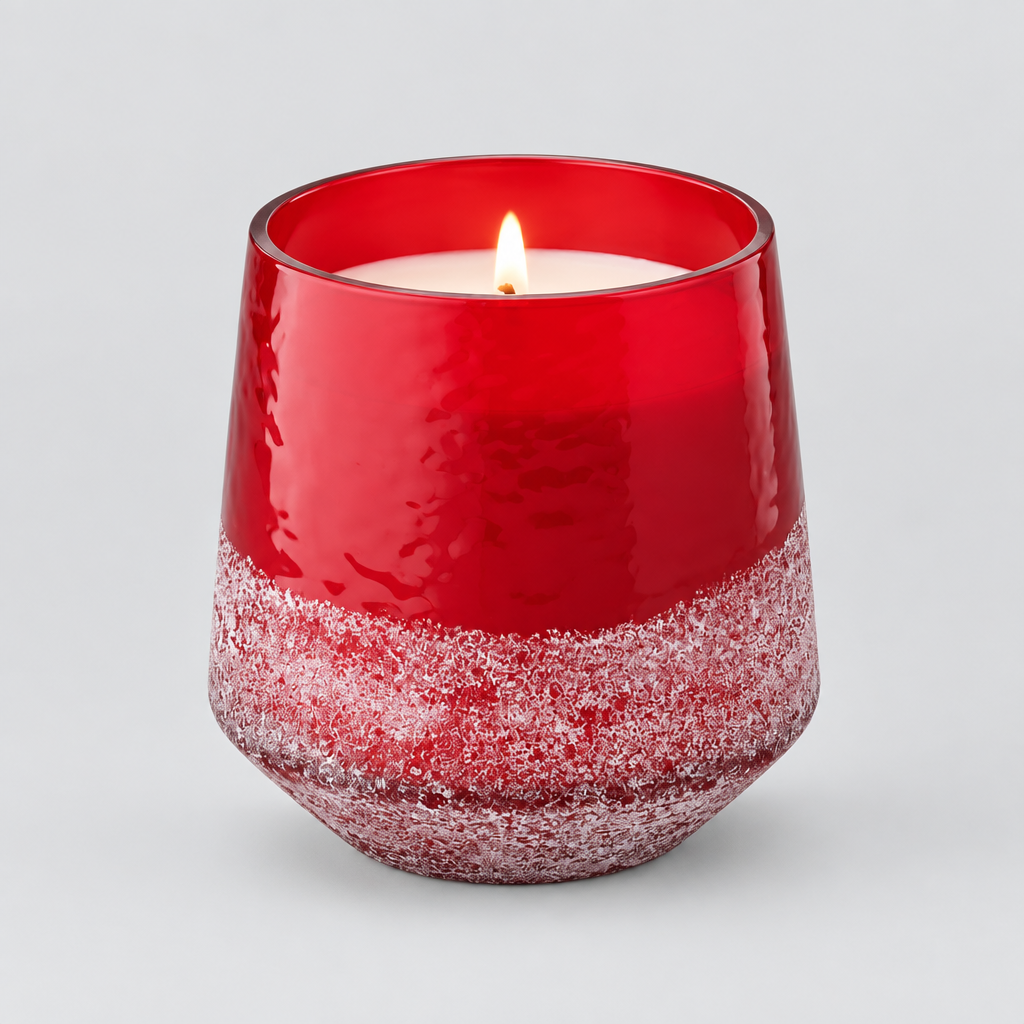 A lit red glass candle in a tapered, rounded container with a textured frosted lower section, shown on a clean white background.