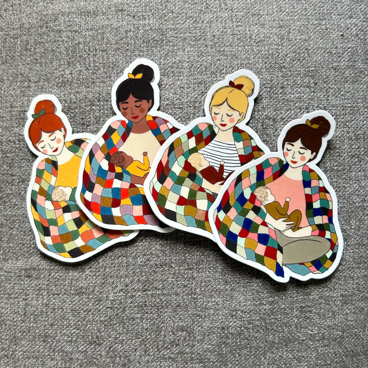 Selection of stickers of mothers holding infants. Each mother has different colored hair and skin tone.