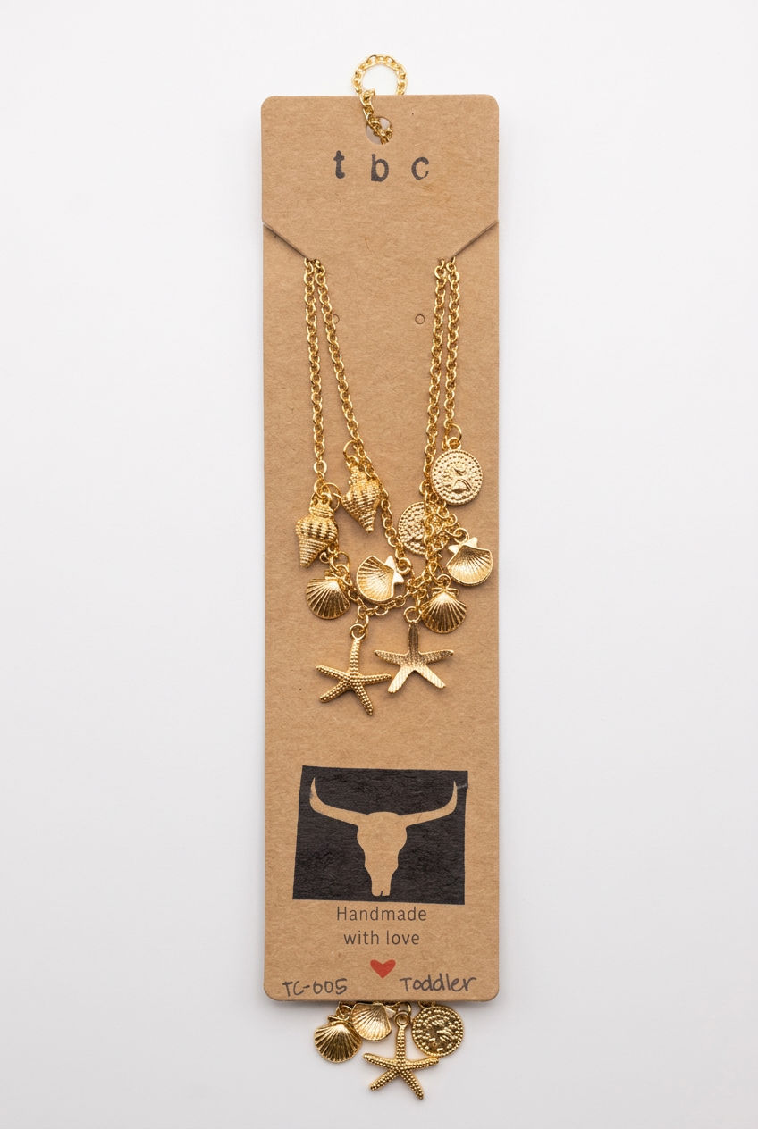 Gold-tone toddler boot charms featuring delicate chains adorned with seashells, scallop shells, and starfish pendants, displayed on a kraft-colored card with a Western-inspired logo.