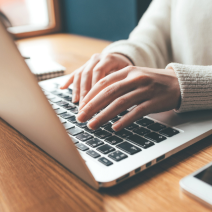 Person using a laptop on a wooden desk with text about curated artisan products.