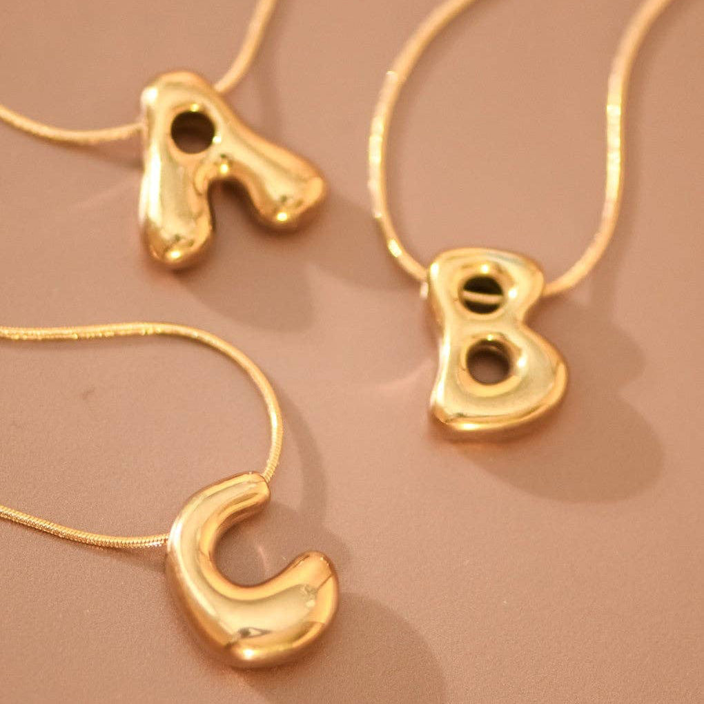 Elevate your everyday style with this 18K gold dipped stainless steel initial necklace. Featuring a bubble letter design, this versatile piece measures approximately 15.75" with a 2" extender for a customizable fit. Hypoallergenic and waterproof, it resists tarnish to maintain its lustrous finish. Available in initials A through Z with select options. To preserve the gold plating's brilliance, avoid prolonged contact with lotions, perfumes, and cleaning products.