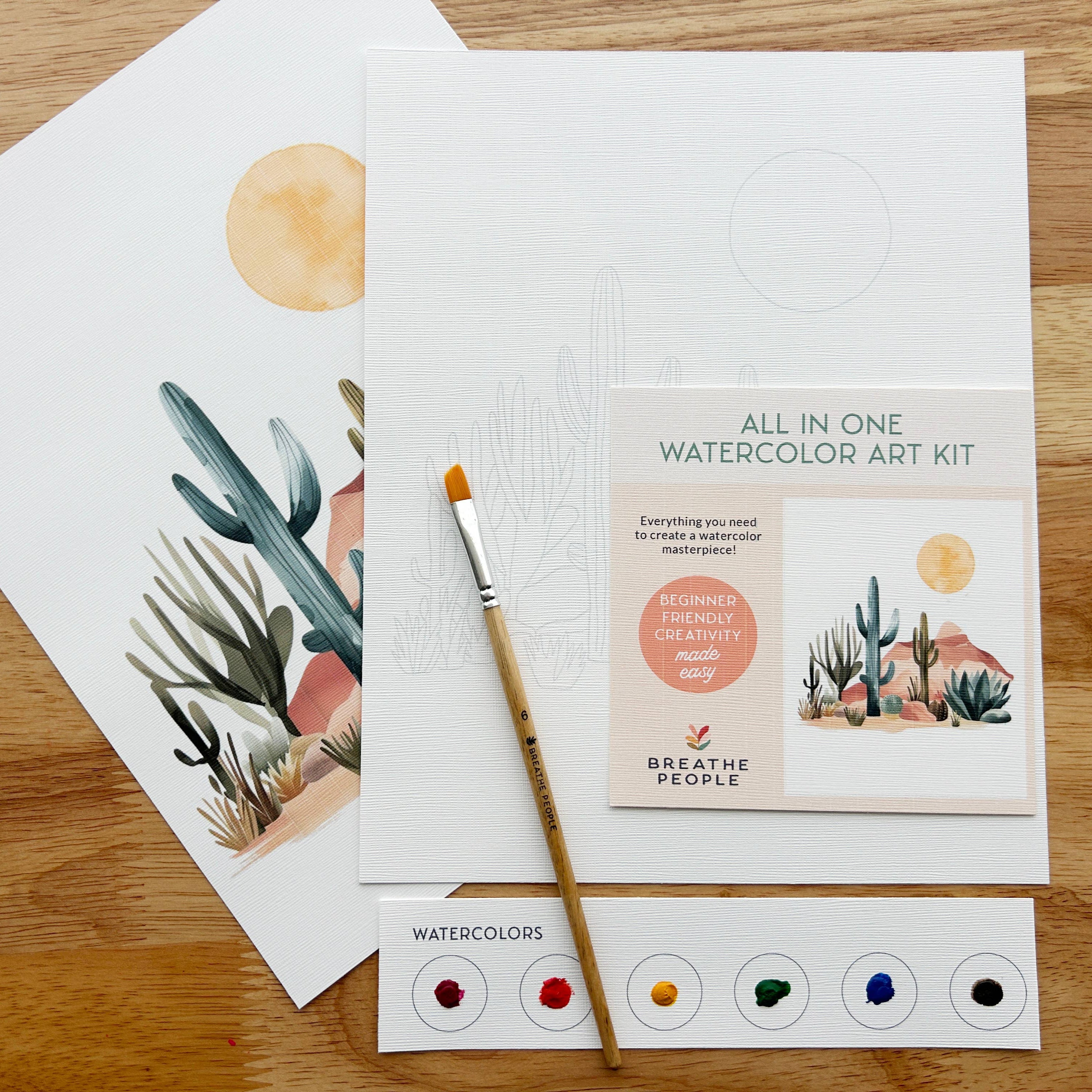 Watercolor art kit with cards and a brush on a wooden surface