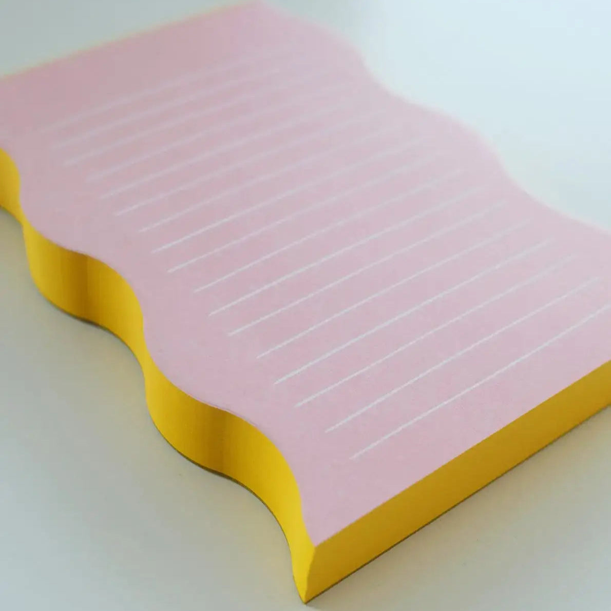 Pink notepad with yellow edge on a white background