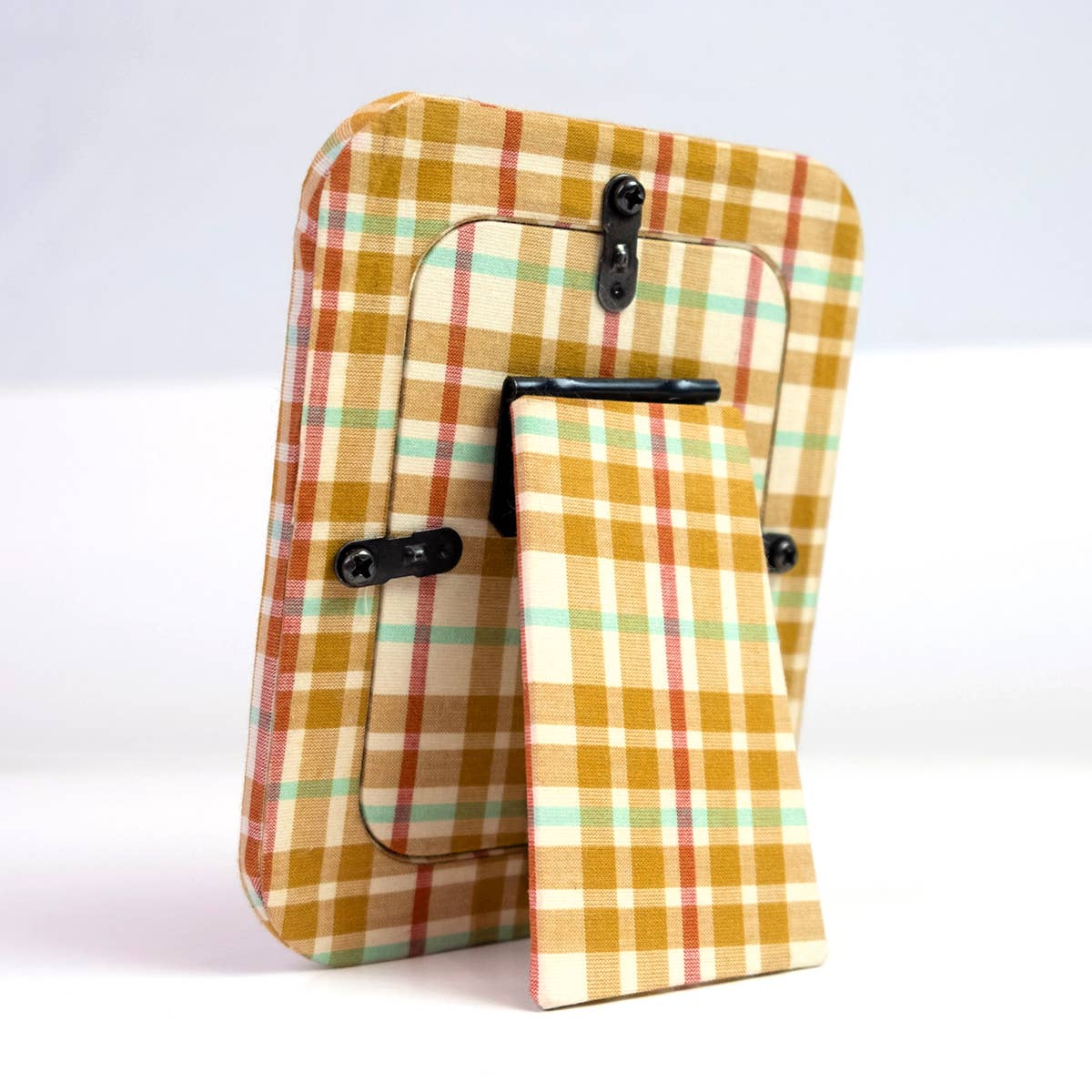A small rectangular tabletop picture frame with a mustard yellow, beige, and mint green plaid border, holding a pink patterned insert card. The card is printed with the brand name 'Handker' and size information.
