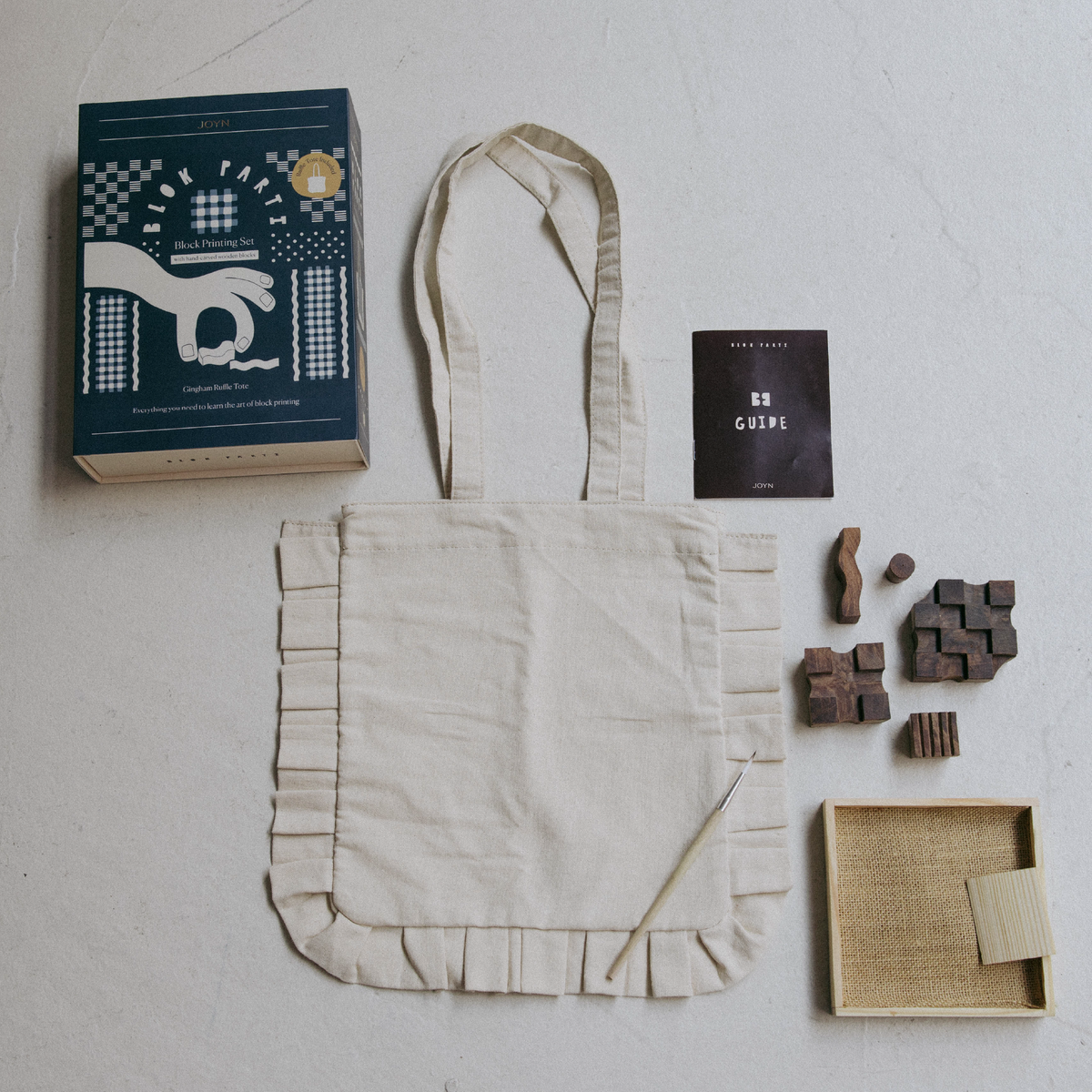 Tote bag with a book, wooden stamps, and a box on a light surface