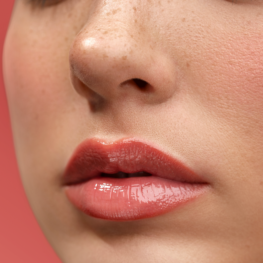 Close-up of a woman's lips with a soft pink lipstick on a blurred background