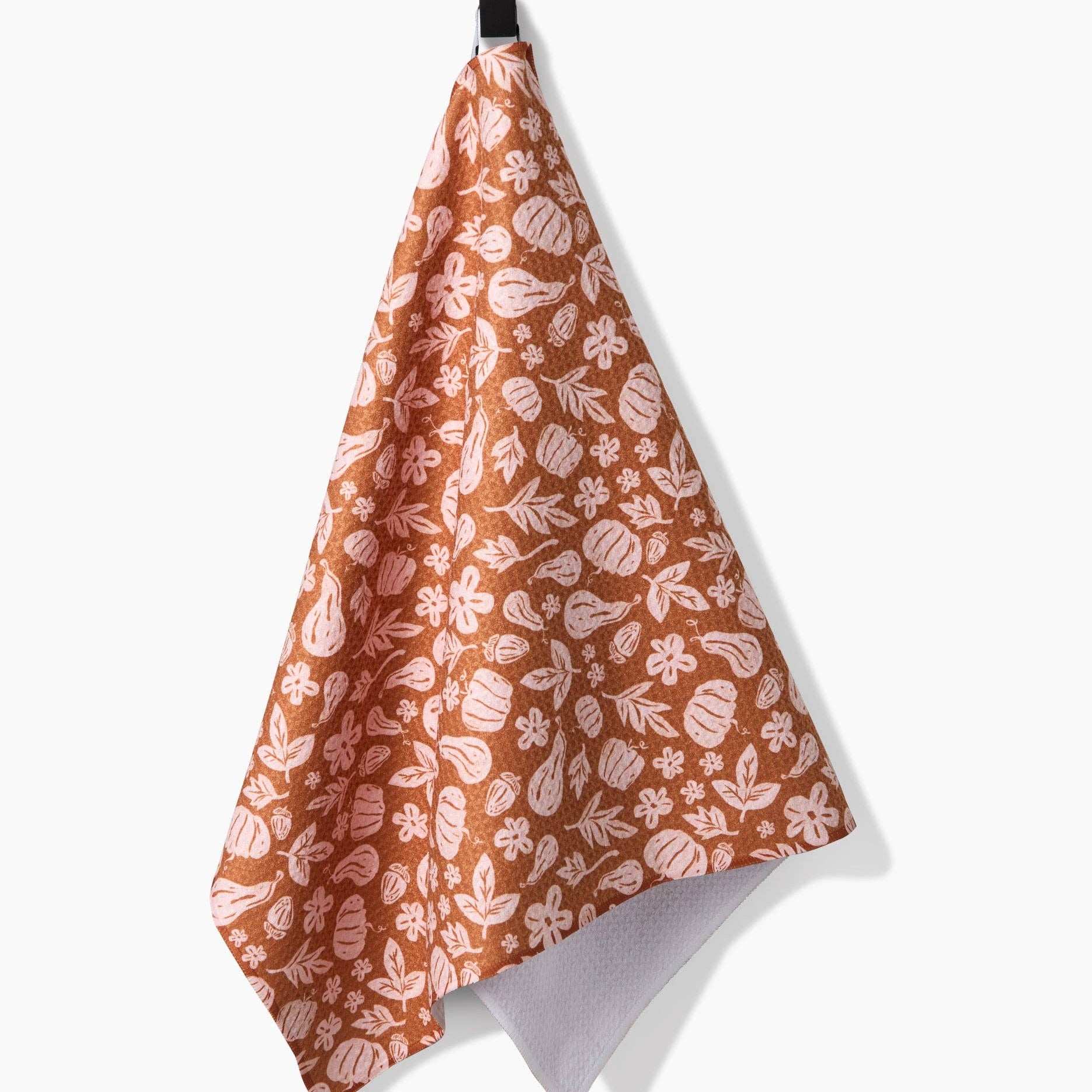 Pumpkin and leaf patterned towel hanging on a hook against a white background
