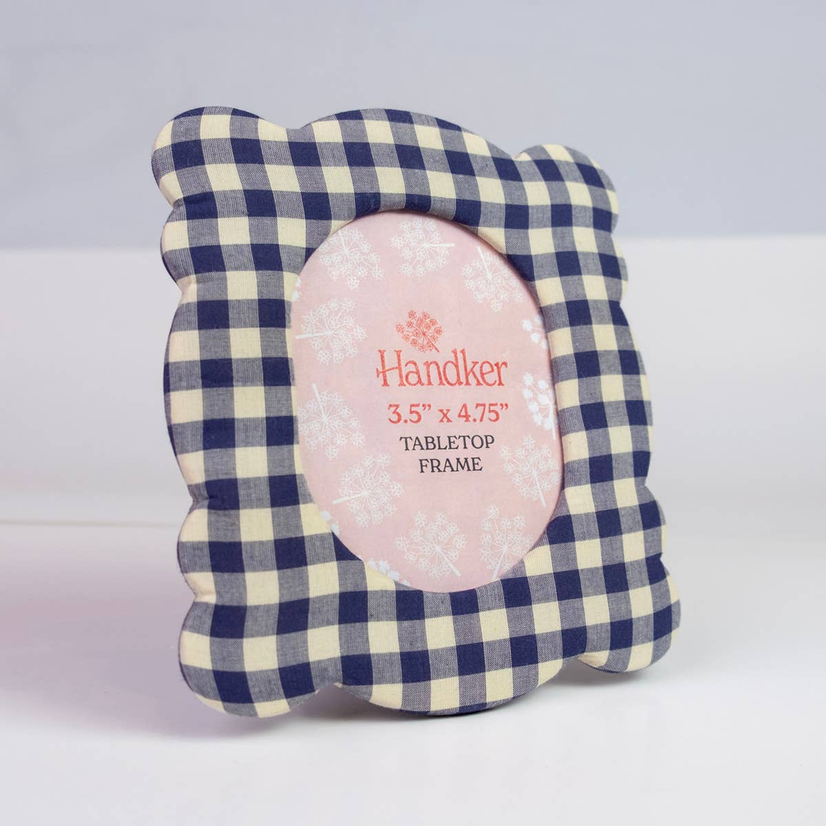 A scalloped picture frame with a navy blue and cream gingham pattern, featuring a pink oval center insert with the brand name Handker.