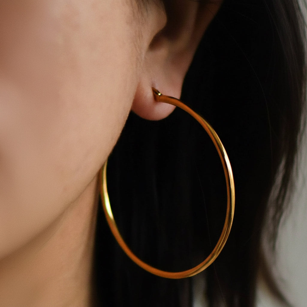 Elevate your jewelry collection with these stunning 18K gold plated hoop earrings, measuring approximately 2 inches in length. Crafted from hypoallergenic stainless steel, they're perfect for sensitive skin and designed to withstand daily wear with their waterproof and tarnish-resistant properties. To maintain their lustrous finish, avoid prolonged contact with lotions, perfumes, and cleaning products. A versatile accessory that combines durability with timeless elegance.