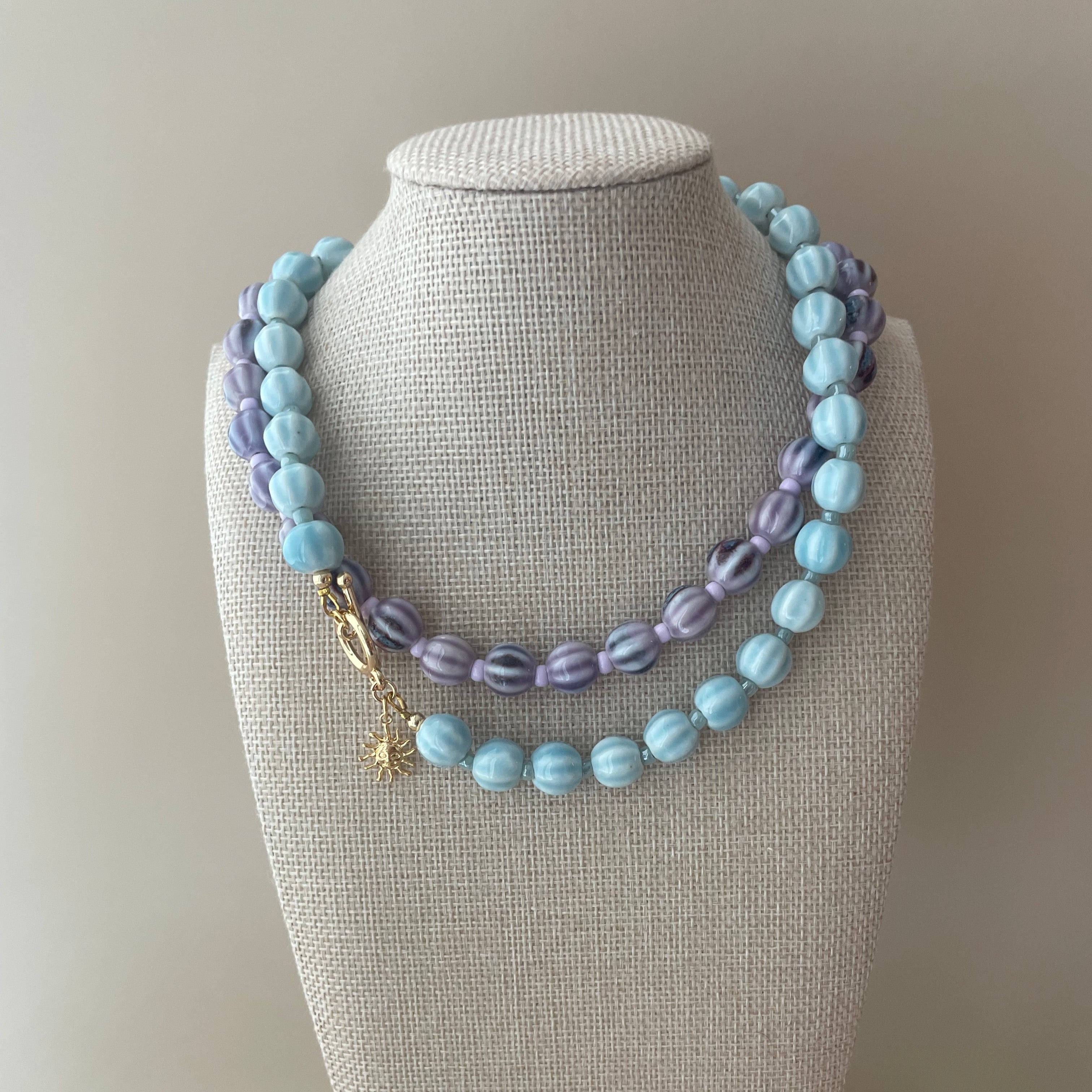 handmade ceramic beaded necklaces in various colors, with gold detail clasp
