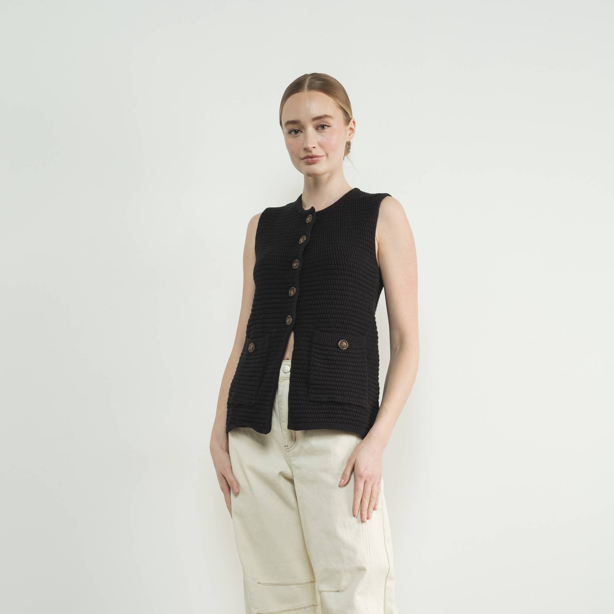 This black sweater vest is the epitome of cozy-chic style, featuring allover ribbed texture and classic button-up closure for a refined yet modern aesthetic. Designed for versatility, it can be worn as a standalone statement. Fitted silhouette that beautifully enhances femininity and complements any outfit. 