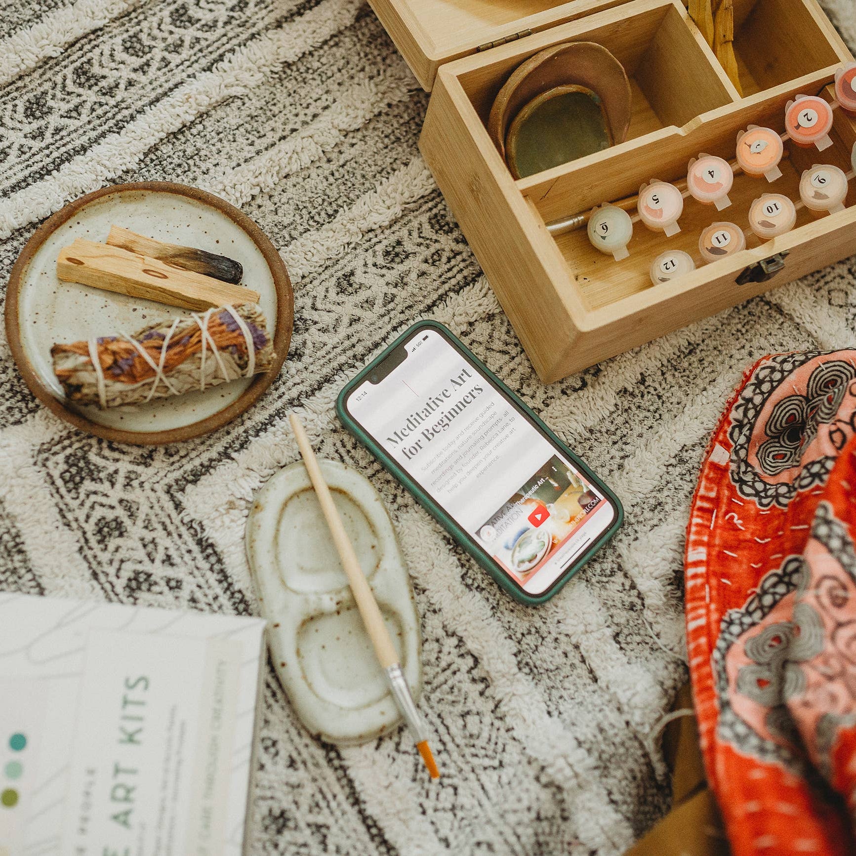 Tabletop with a phone, incense, and other items on a patterned surface