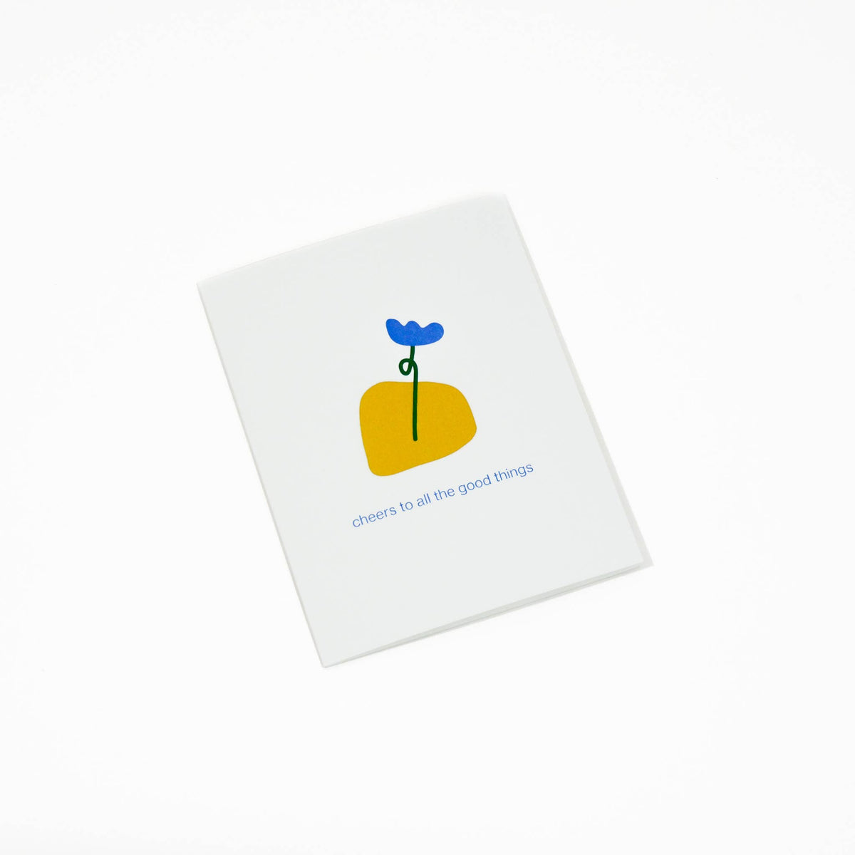A white greeting card with a minimalist illustration of a yellow flower with a blue bloom and the text 'cheers to all the good things' printed below, shown on a clean white background.