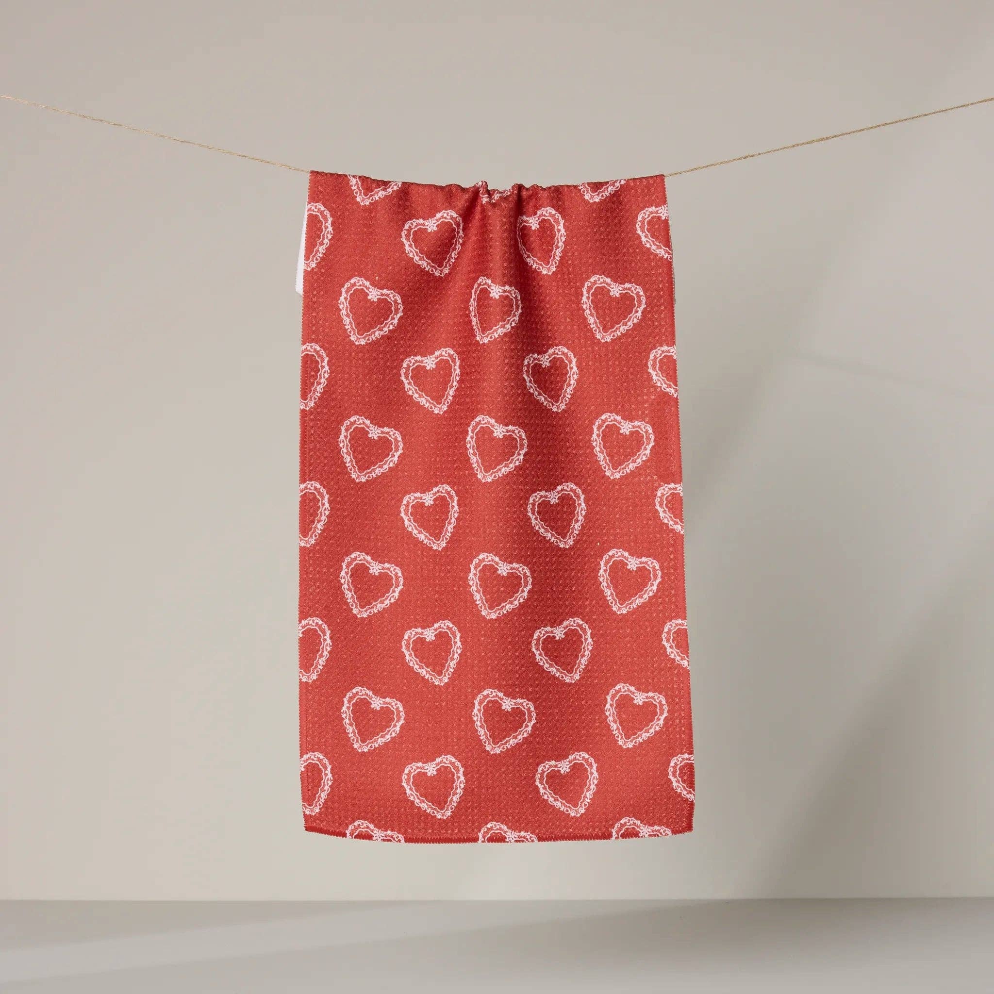 Red fabric with white heart patterns hanging on a line against a plain background Tea Towel
