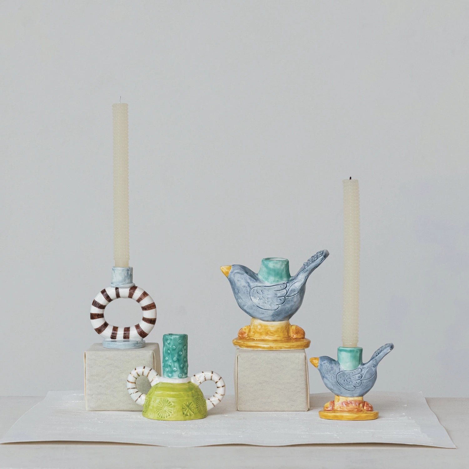 Elevate your decor with our Hand-Painted Stoneware Ring Taper Holder. Each one is carefully crafted and adorned with vibrant stripes, making it a unique and eye-catching piece. Perfect for holding taper candles, this holder adds a touch of style and functionality to any space. 4"L x 2-1/2"W x 4-3/4"H Striped