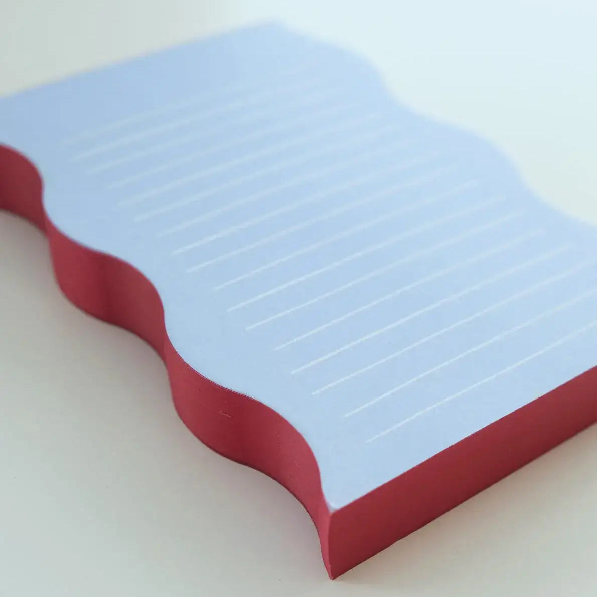 Notepad with red border and blue lined pages on a white background