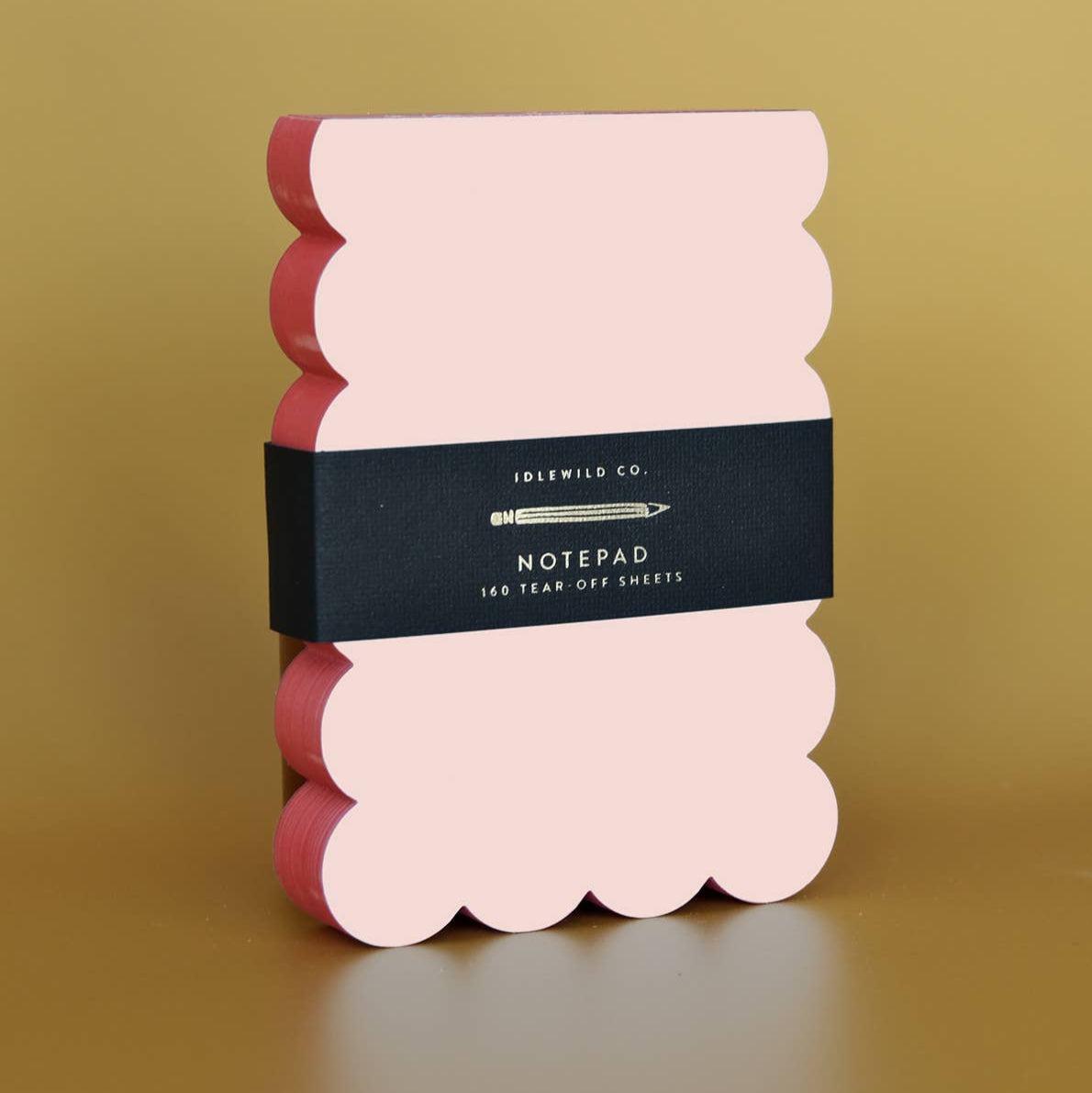Notepad with scalloped edge design on a gold background