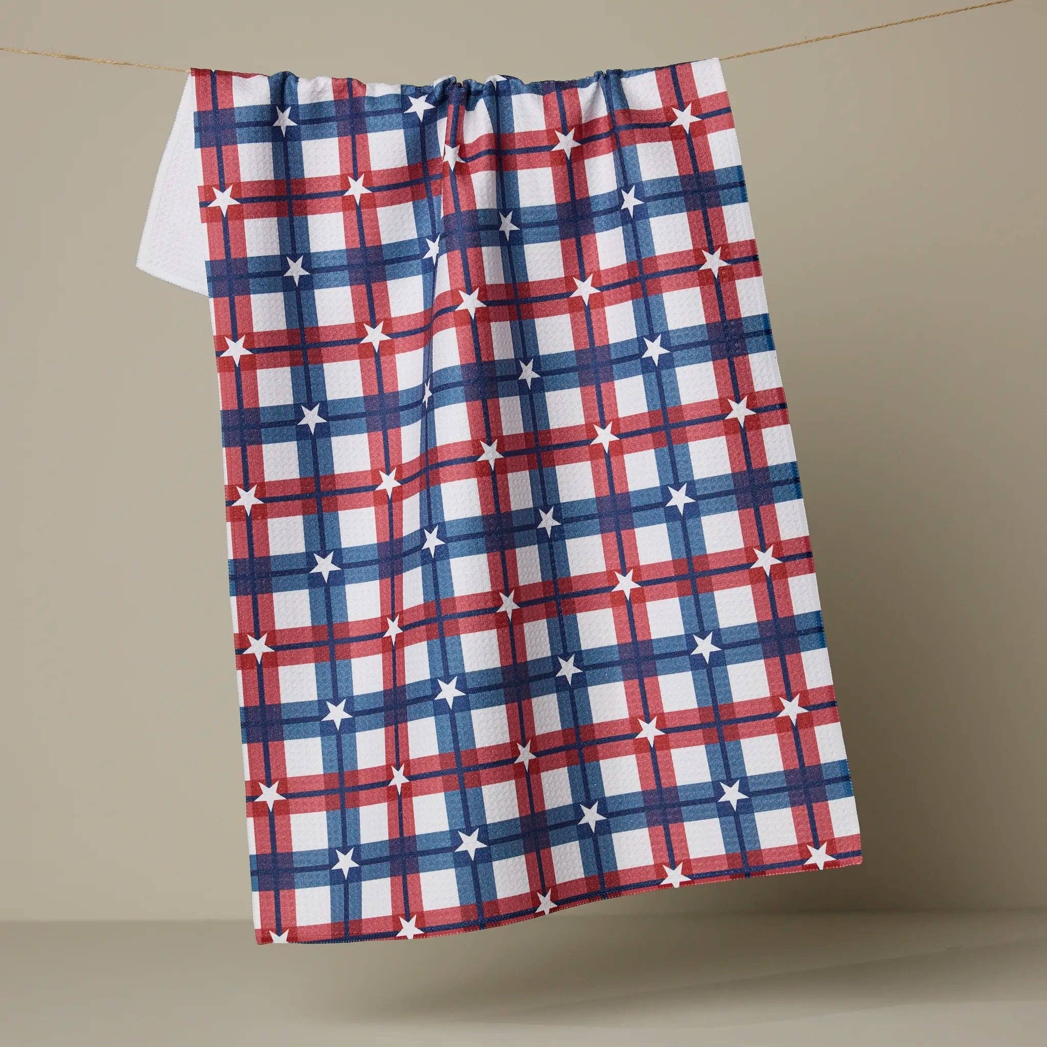 Red, white, and blue plaid towel hanging on a line against a beige background