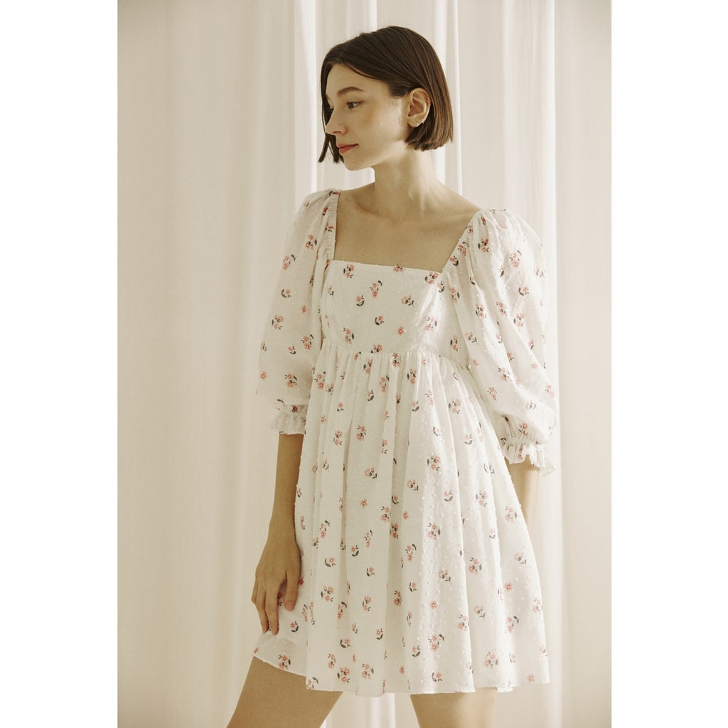 Embroidered little flowers and swiss dot baby doll mini dress. It displays a square neckline, 3/4 puffy sleeves, and two bust darts. It also has an empire gathered waist and a back zipper for off/on access.