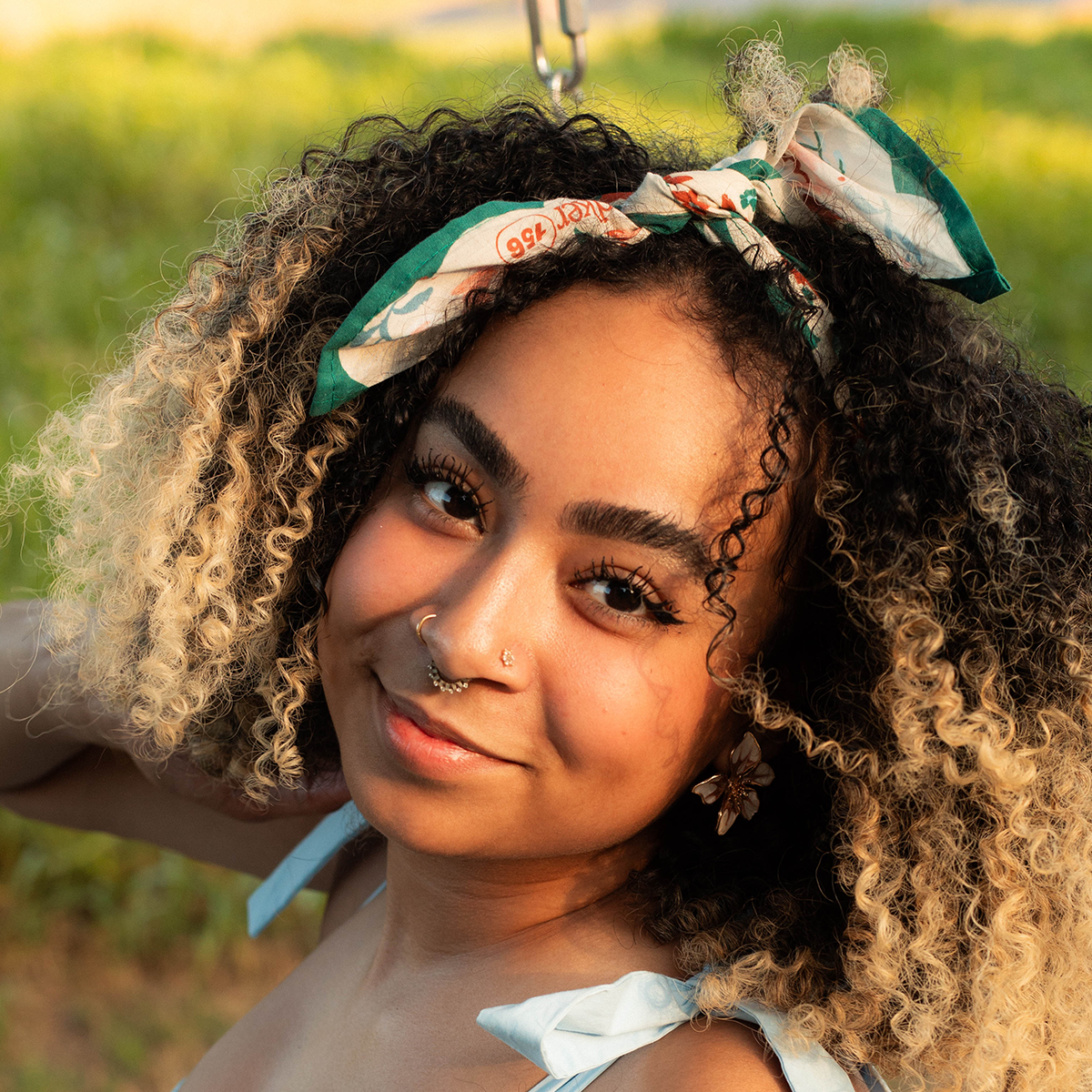 Woman with curly hair wearing a floral headband in a natural setting
