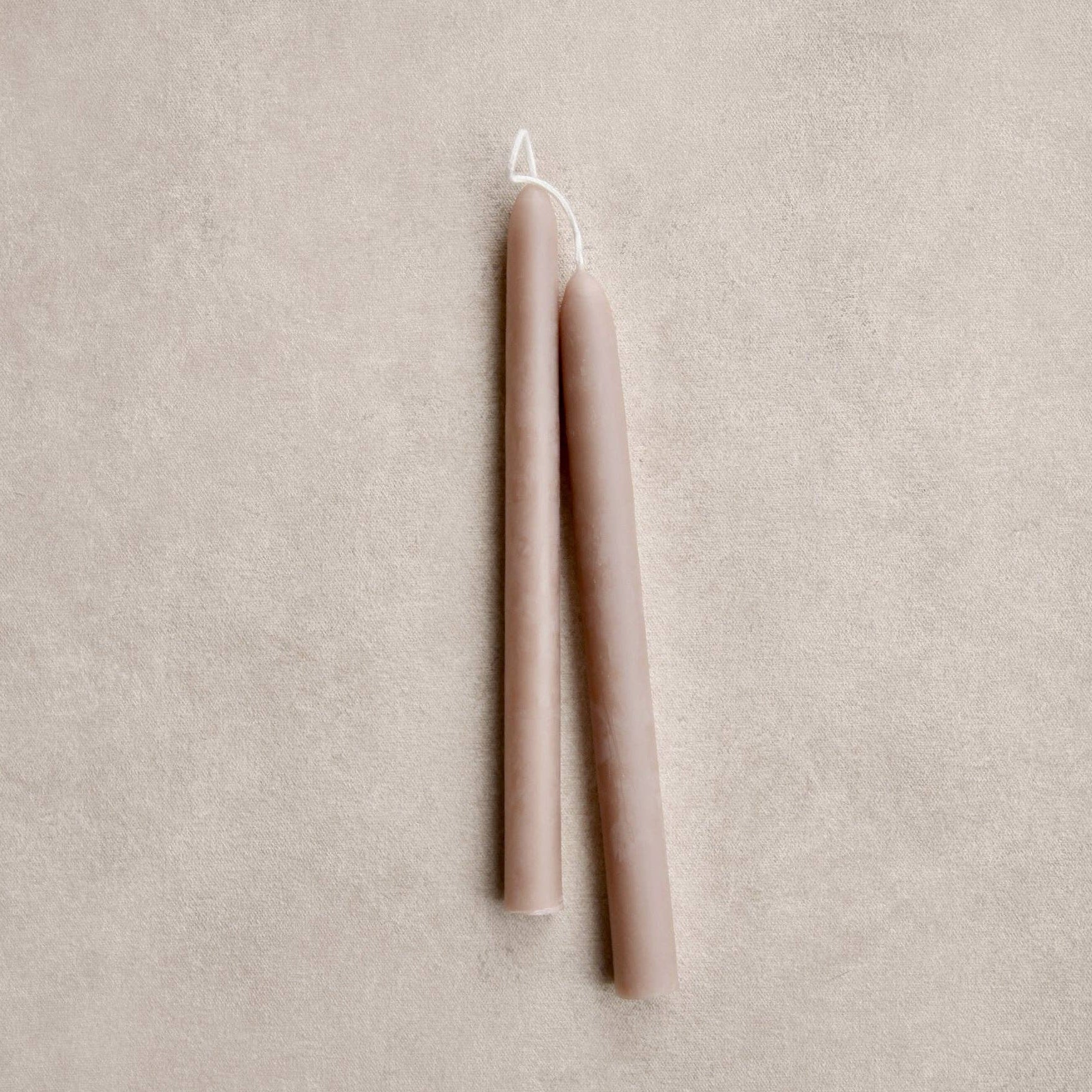 Two beige candles on a mushroom color