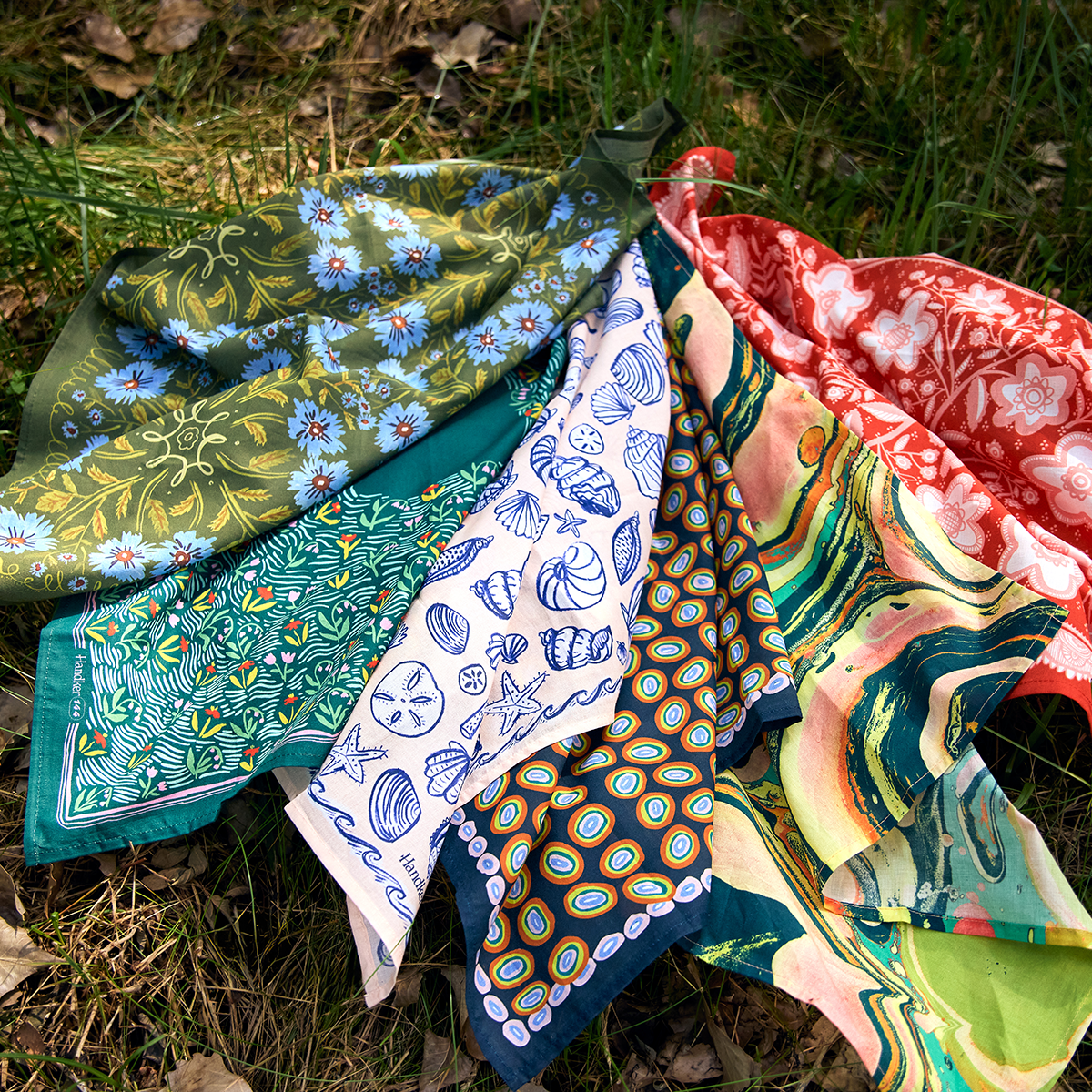 Colorful patterned scarves on a grassy background