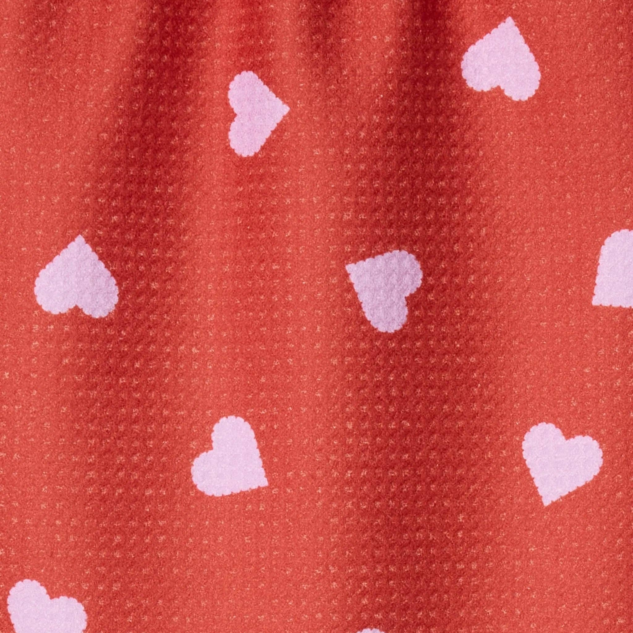 Close-up of a red fabric with pink heart patterns