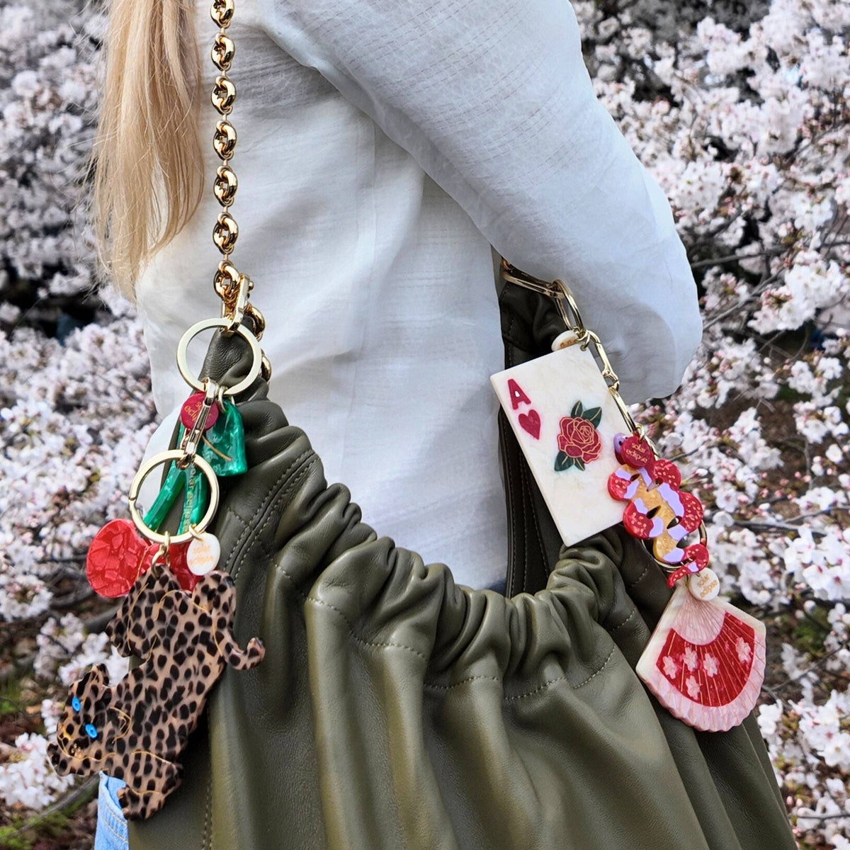 Person holding a bag with decorative keychains against a cherry blossom background