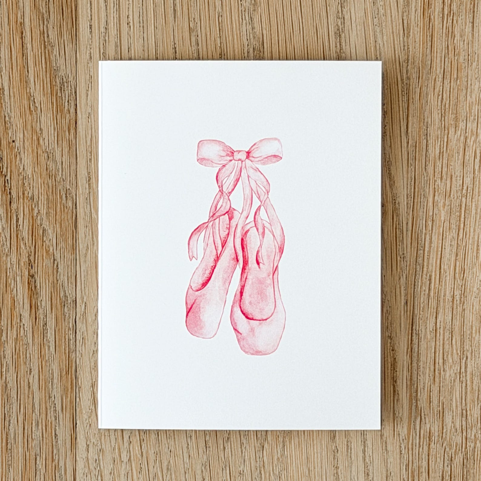 White print with pink ballet shoes laced into a bow.