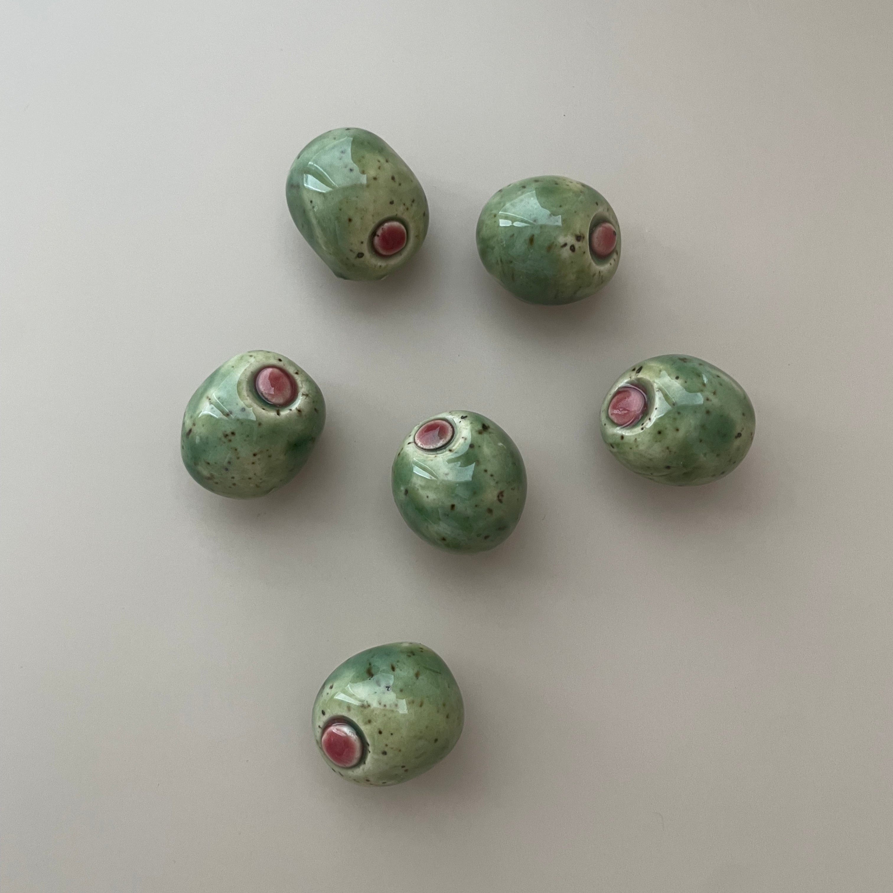green olive magnet with pimento detail and a green glaze with brown specks
