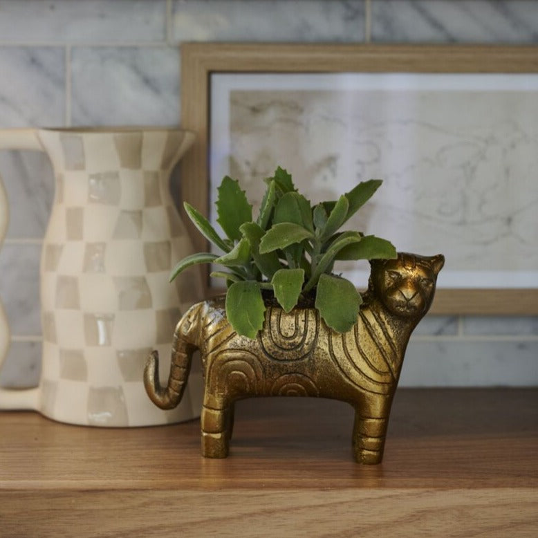 Behold the whimsical charm of the Tiger Pot, a recycled cast aluminum curiosity. This watertight piece is designed to fit a 2-inch drop-in pot, or it can be used as a decorative piece with an air plant or nothing at all on a desk or bookshelf. Crafted from a hand-carved mold, this sculptural vessel with its antique gold finish showcases handcrafted artistry & timeless beauty in every detail.