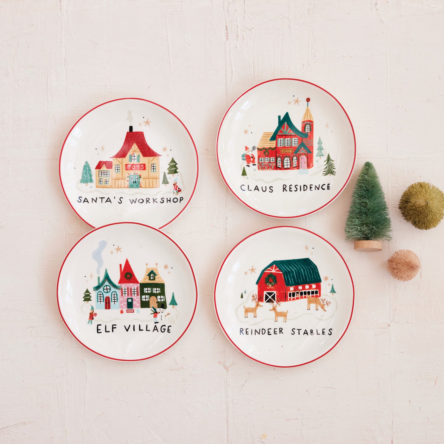 Four Christmas-themed plates with illustrations of houses and text on a white background