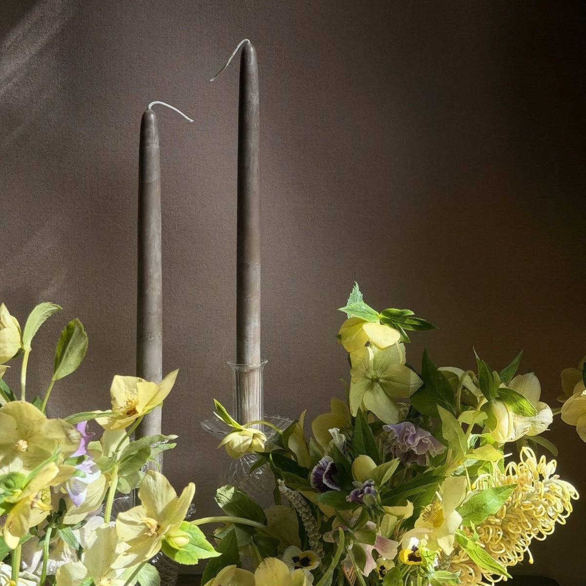 Two dark candles with floral decorations on a dark background