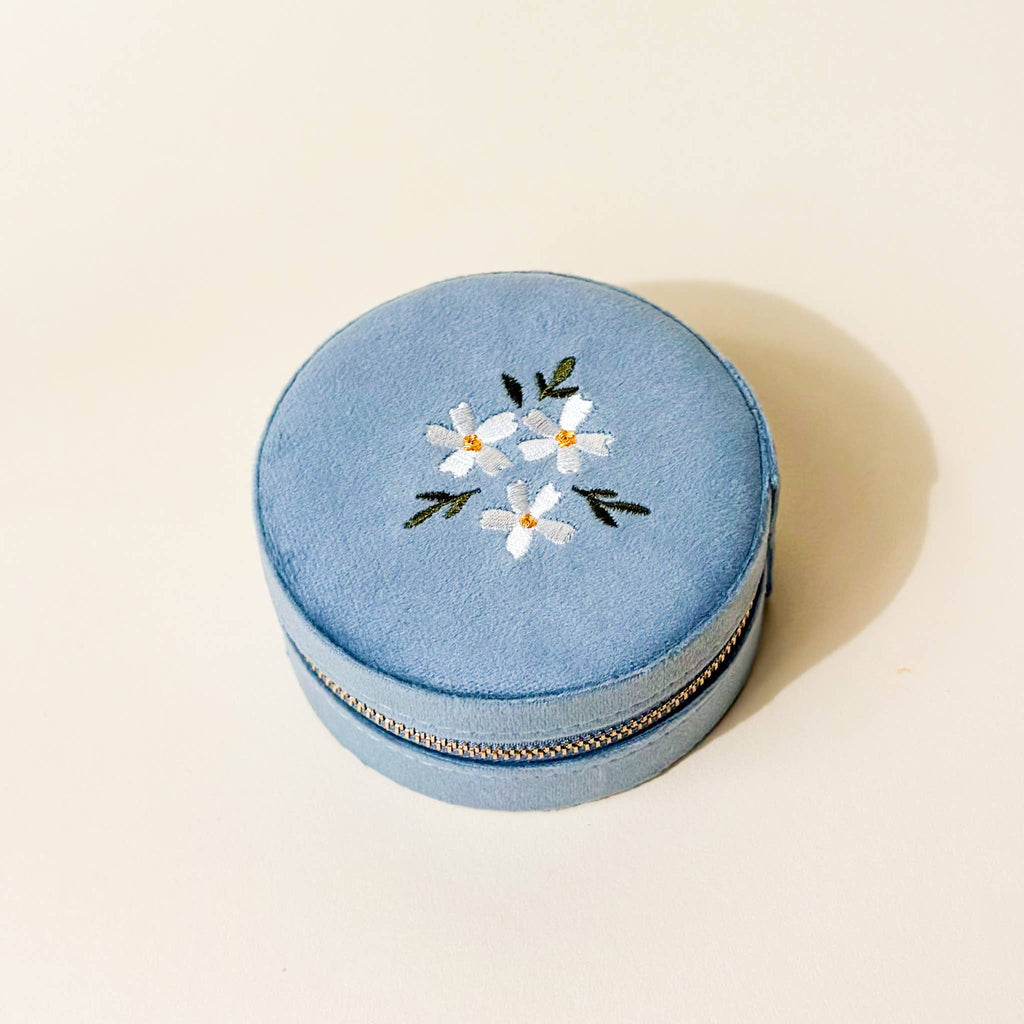 Your new adorable solution for keeping accessories safe and organized on the go! On the outside, this case features a stunning floral embroidered lid and gleaming gold zipper hardware. Inside, you'll find 5 slots for rings or earrings, an interior lid pouch, and open storage space for larger pieces.

Details:

Dimensions: 3” Round x 1.75” Thick
WARNING: Cancer and Reproductive Harm - www.P65Warnings.ca.gov