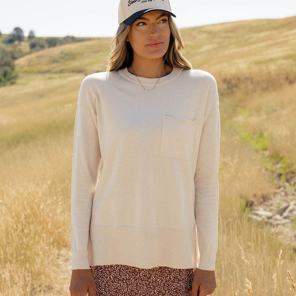 Featuring a playful high-low hemline and whimsical side slits, this sweater is as stylish as it is comfy! With ribbed details, a patch pocket, and a relaxed boxy fit, you'll feel warm and wonderful all day long. Ivory