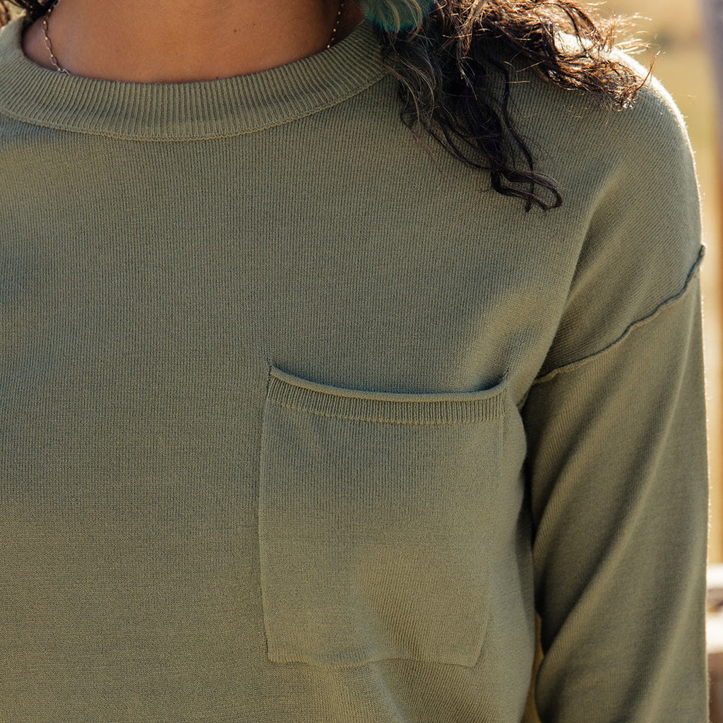 Featuring a playful high-low hemline and whimsical side slits, this sweater is as stylish as it is comfy! With ribbed details, a patch pocket, and a relaxed boxy fit, you'll feel warm and wonderful all day long. Olive Drab