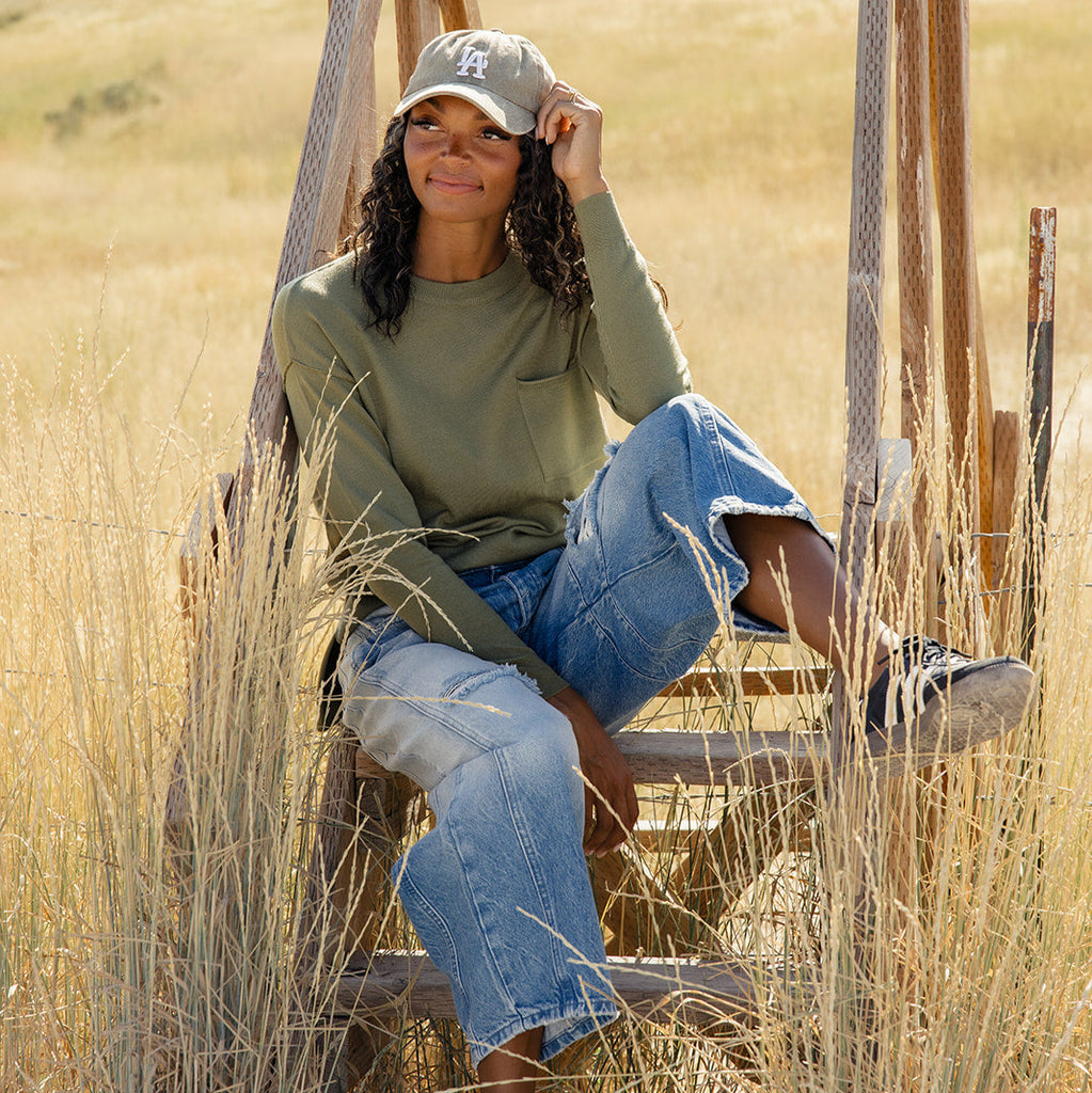 Featuring a playful high-low hemline and whimsical side slits, this sweater is as stylish as it is comfy! With ribbed details, a patch pocket, and a relaxed boxy fit, you'll feel warm and wonderful all day long. Olive Drab