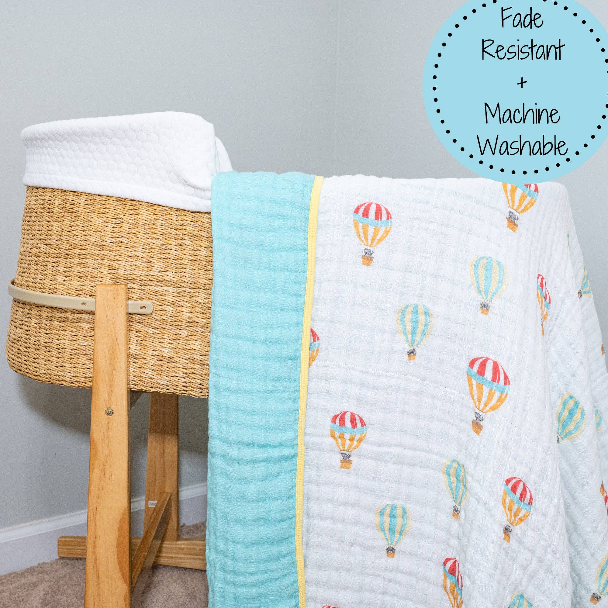 Baby crib with a quilt featuring hot air balloon patterns and a wicker basket.