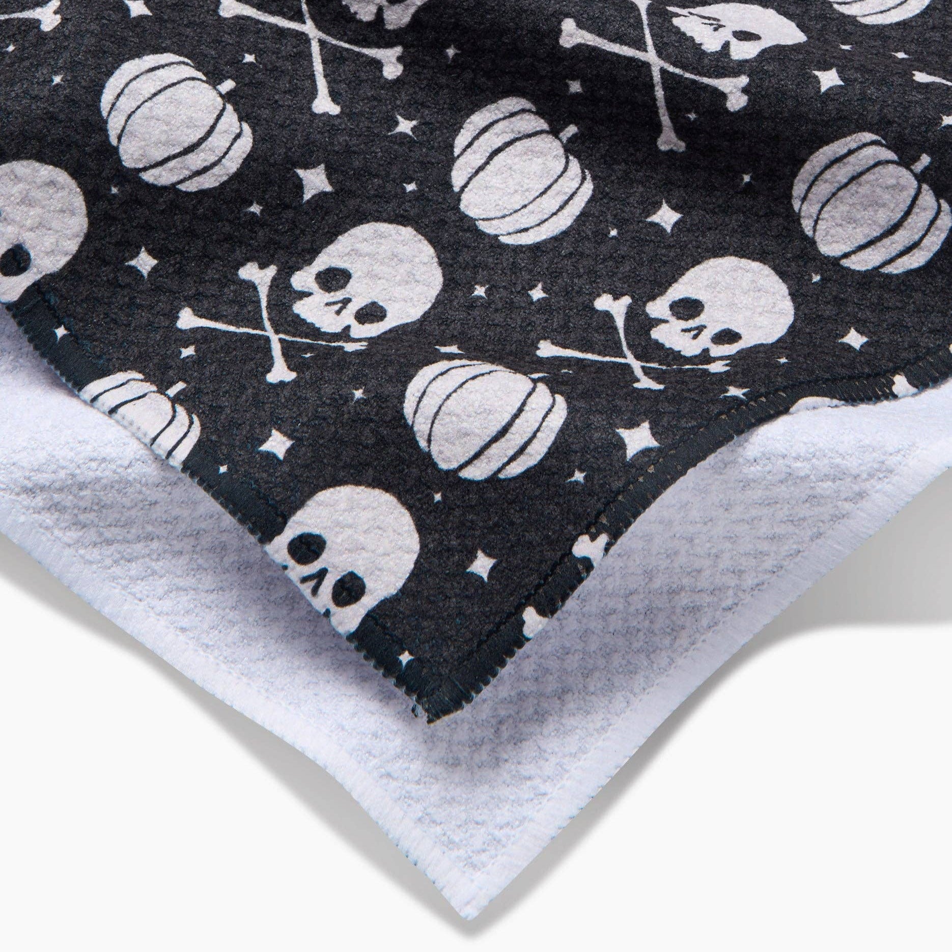 Black fabric with white skull and pumpkin pattern, showing a close-up of the texture.