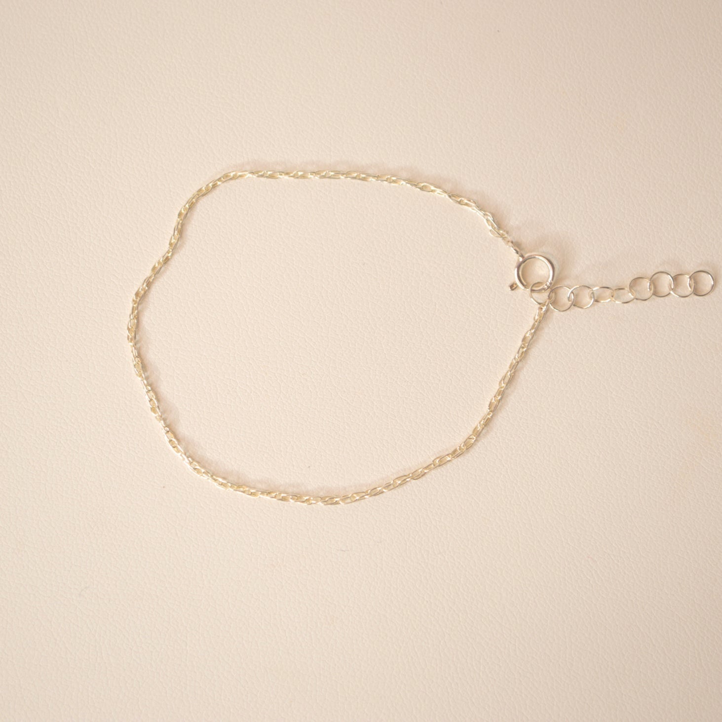 Silver bracelet against an off white back ground. 
