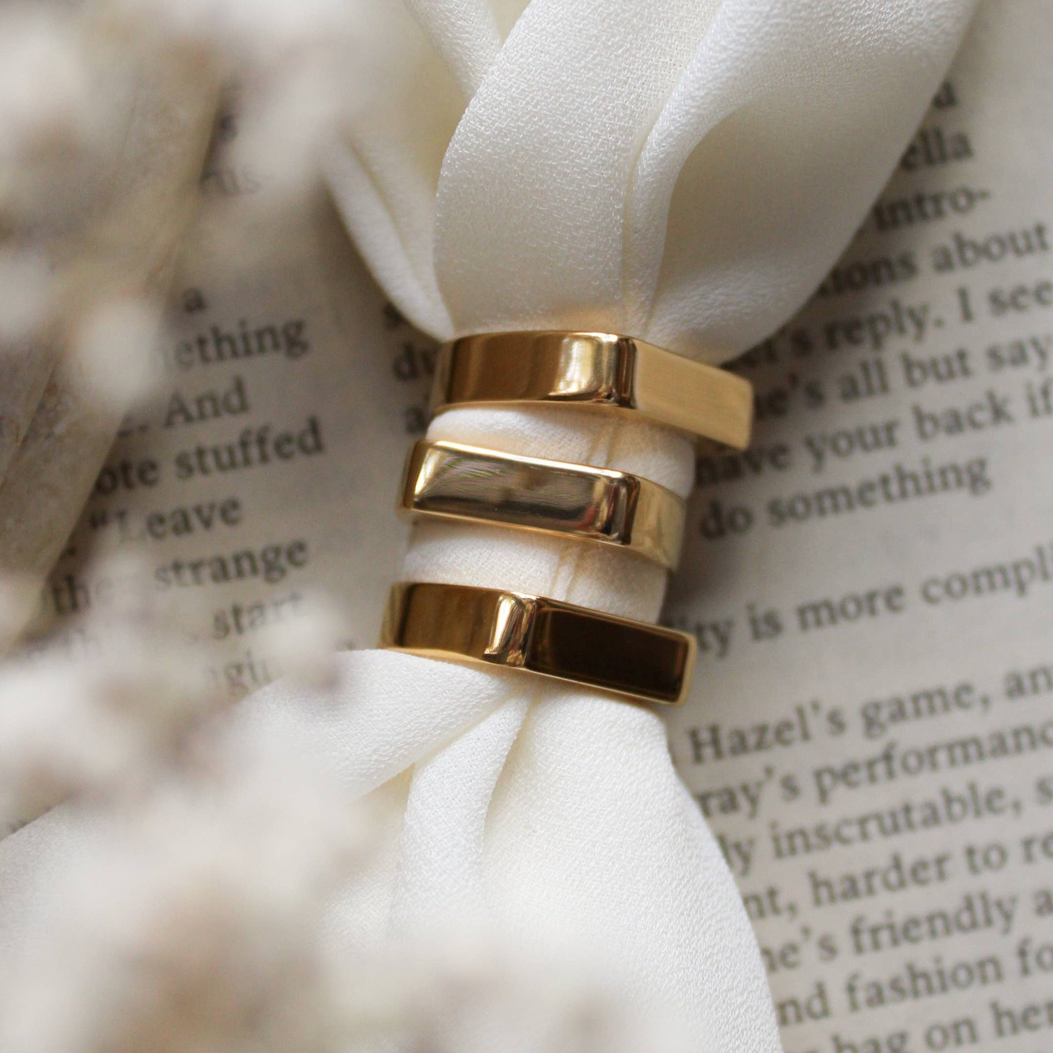 Gold ring on a white flower with a blurred book page in the background