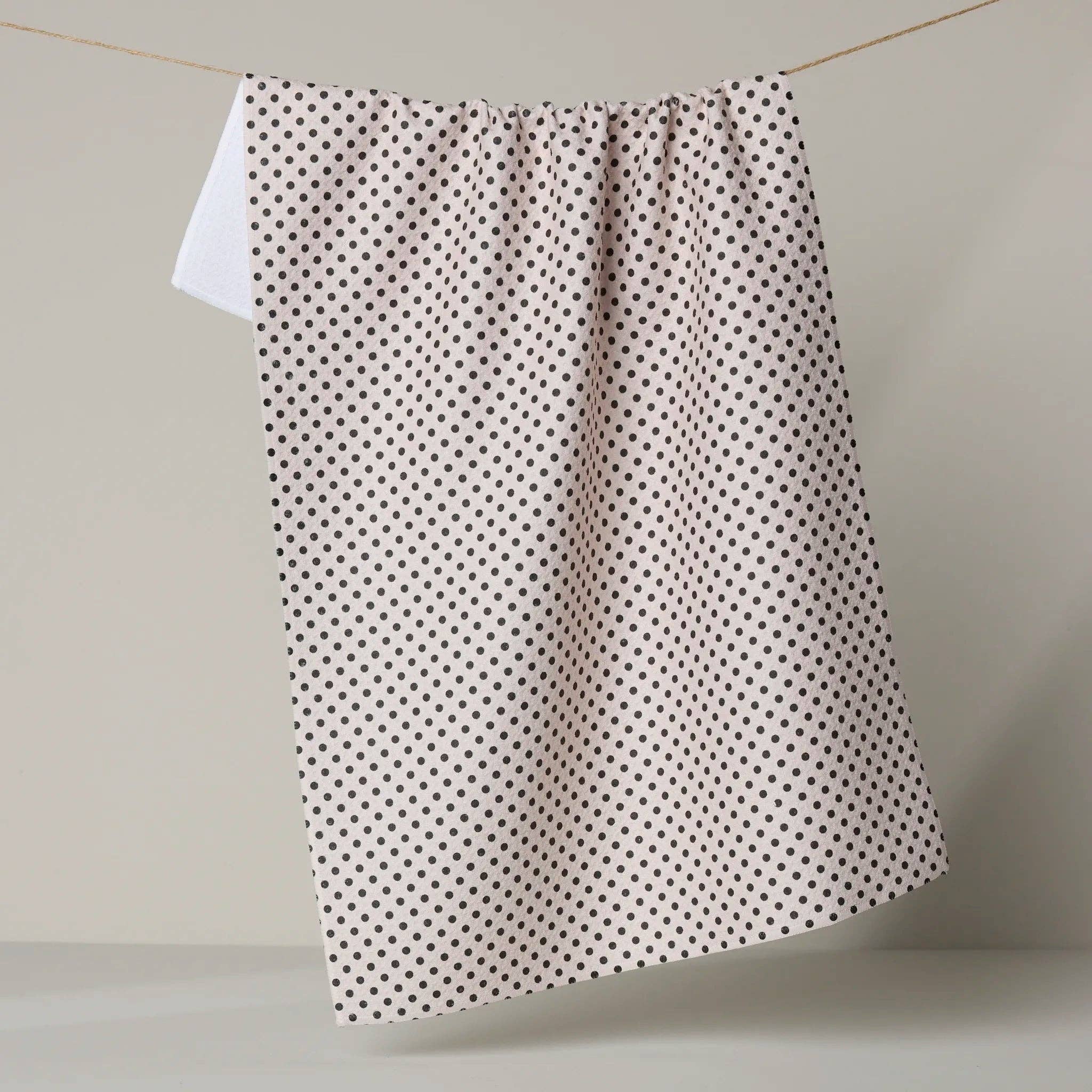 Polka dot tea towel hanging on a line against a neutral background