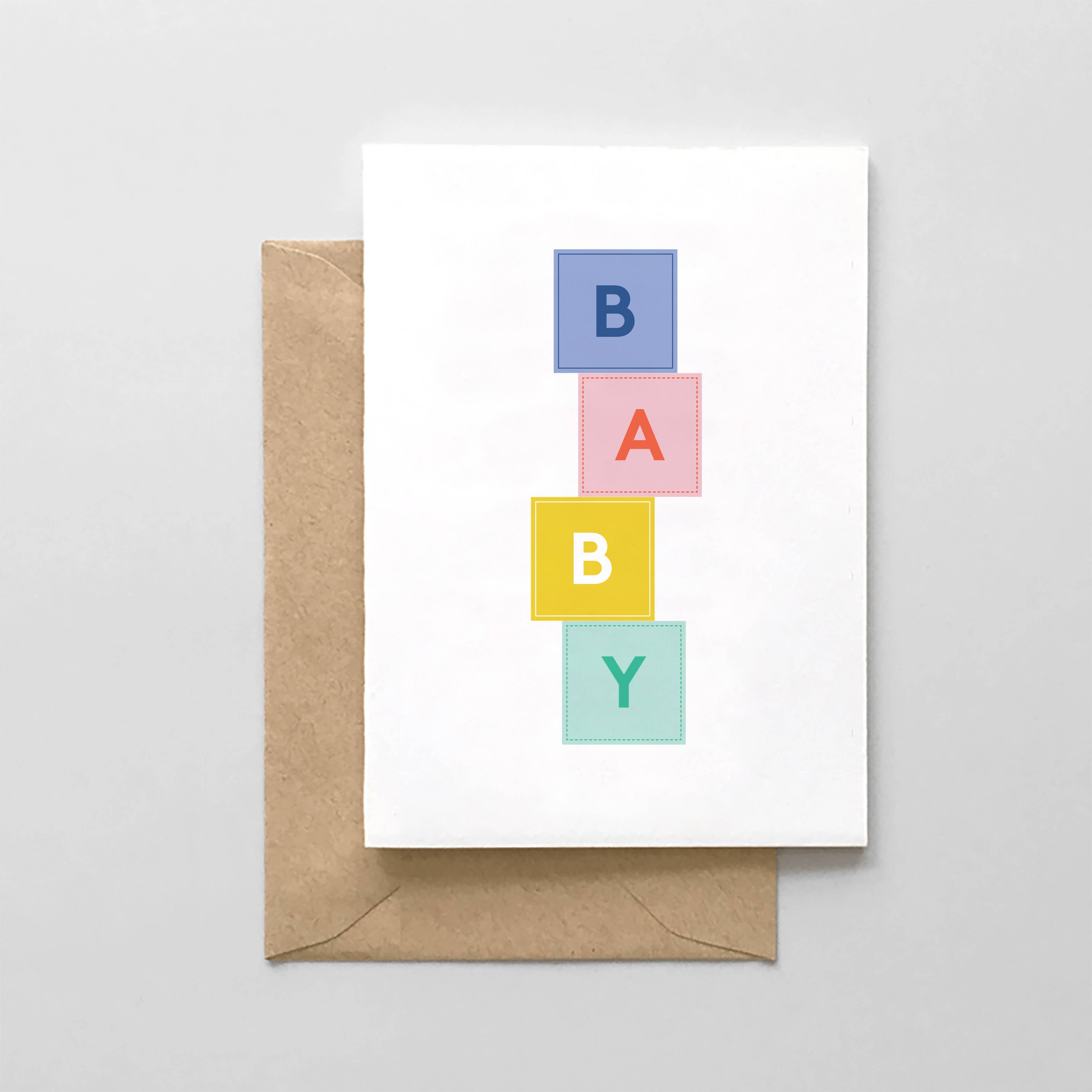 Greeting card with colorful 'BABY' blocks and a brown envelope on a light gray background