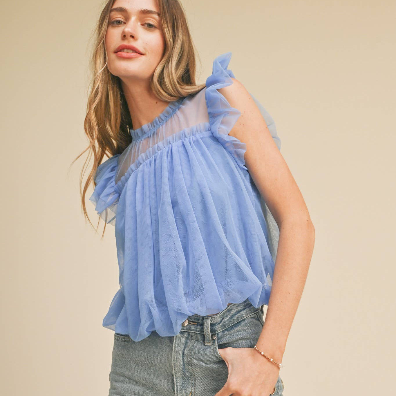 Embrace your softer side in this charming mesh ruffled flutter sleeve top. The delicate high ruffled neckline and playful flutter sleeves create an effortlessly romantic silhouette that celebrates your femininity. A bubble hem adds gentle movement and dimension, while the keyhole back with button closure offers a sweet surprise detail. Fully lined for comfort and confidence. Perfect for anyone seeking a piece that feels as good as it looks—a wardrobe staple that reminds you to be kind to yourself.