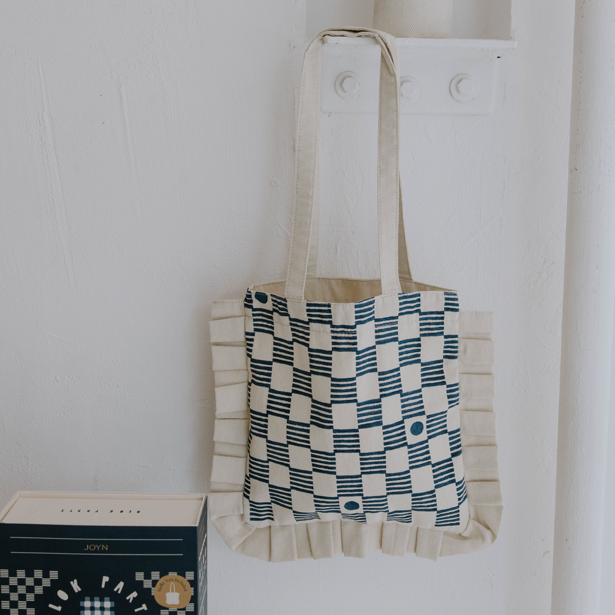 Tote bag with checkered pattern hanging on a white wall